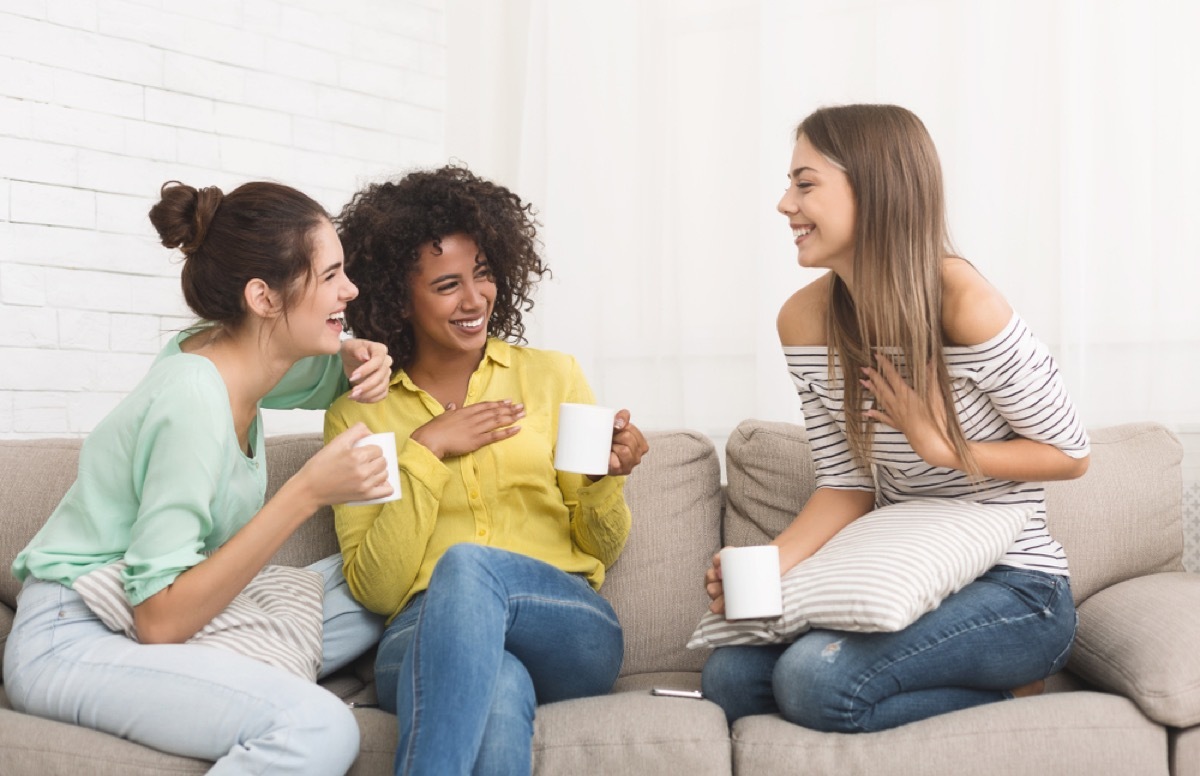 three young women talking and drinking tea on the couch