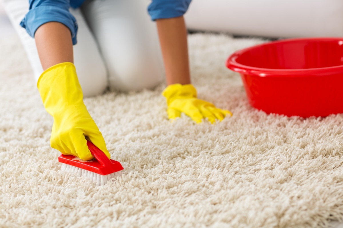 woman scrubbing white rug